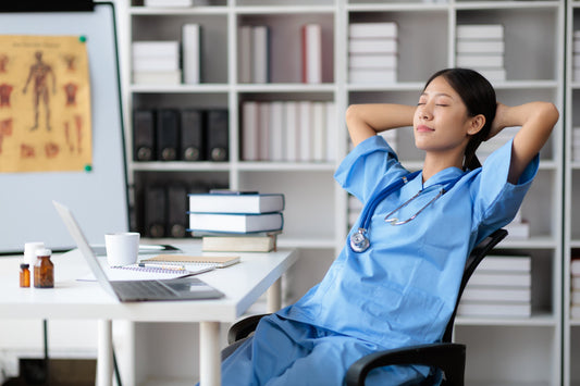 Healthcare worker in scrubs relaxing in office chair during break.
