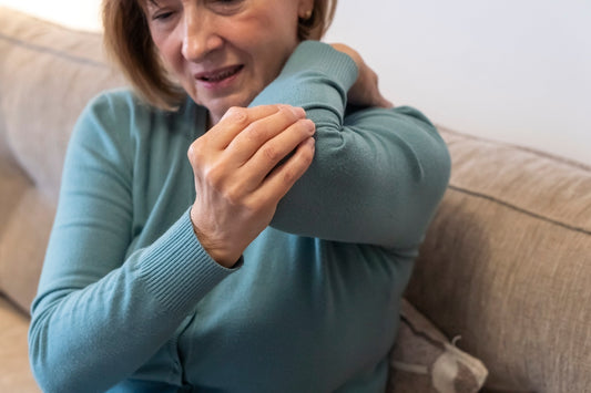 Woman clutching elbow in pain, showing symptoms of tennis elbow or golfer's elbow.