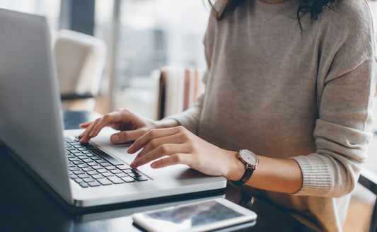Woman typing on laptop, illustrating wrist strain risk from extended computer use.