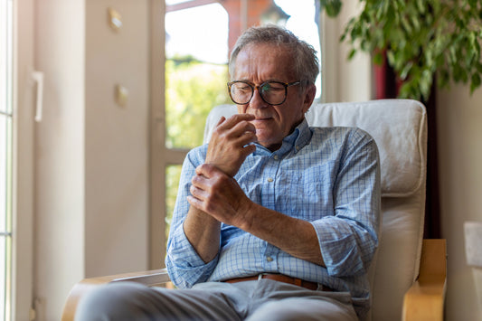 Elderly man holding his wrist in pain, highlighting the need for early wrist support.