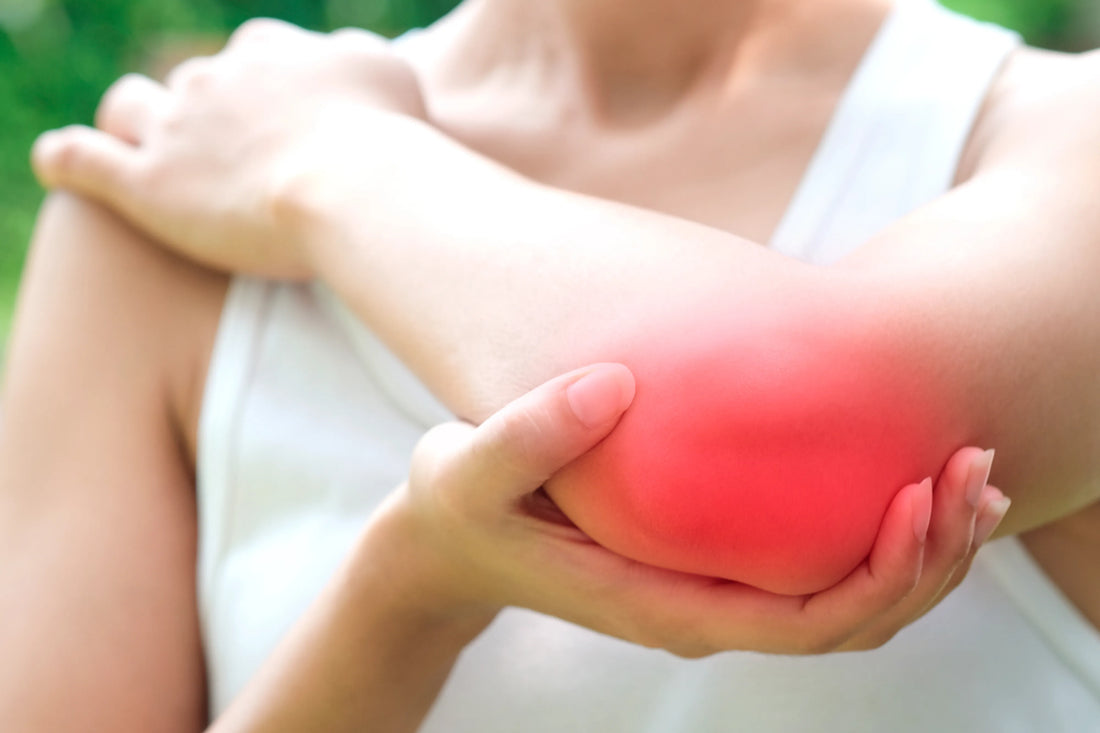 Woman clutching her elbow with a red inflammation highlight indicating inner elbow pain and nerve discomfort associated with cubital tunnel syndrome