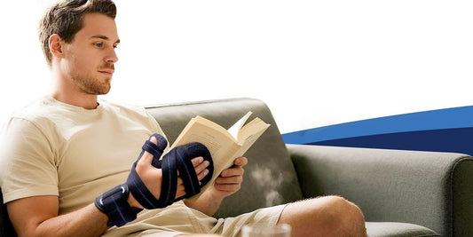 Person reading while wearing a FEATOL resting hand splint with thumb support.