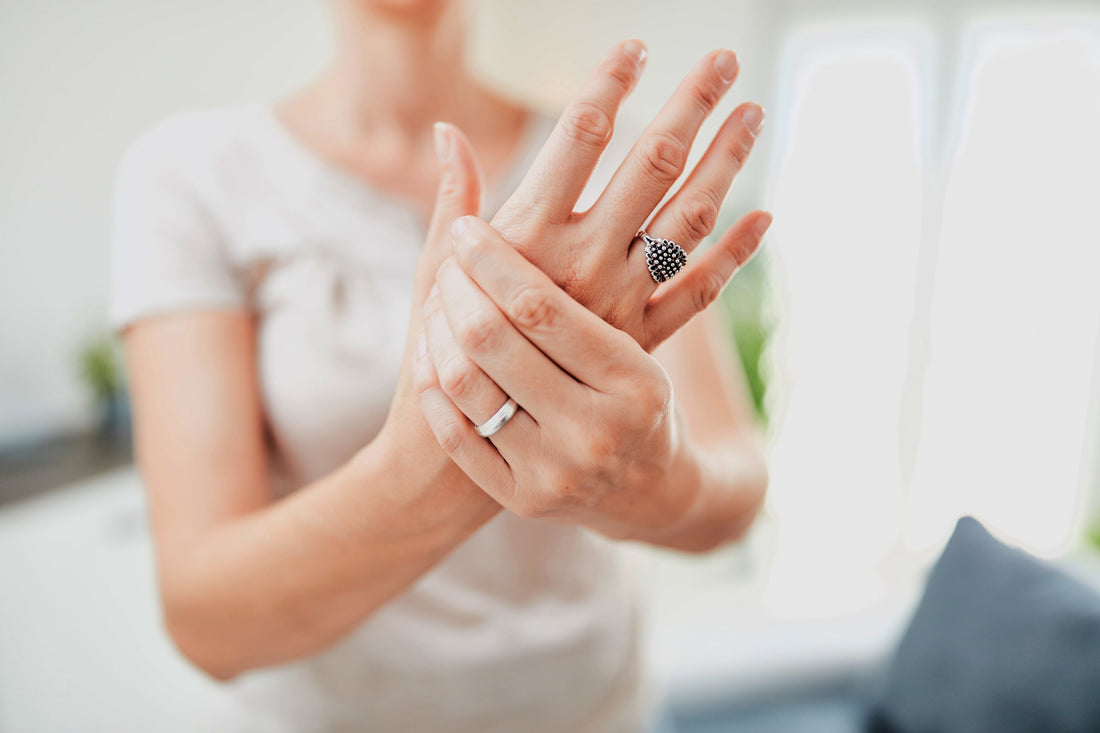 Woman's hands pressing thumb base joint showing pain from CMC arthritis or thumb osteoarthritis