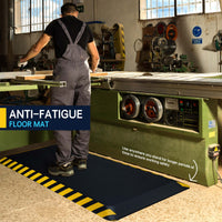 Worker standing on black anti-fatigue mat with yellow border at woodworking workstation in industrial workshop