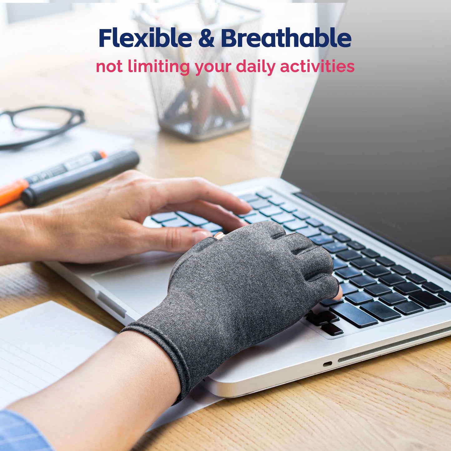 Compression glove worn while typing on laptop, showing flexible fingertip-free design for daily office use.