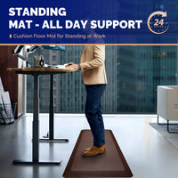 Professional man in beige blazer standing on brown FEATOL anti-fatigue mat at height-adjustable standing desk in modern office, ergonomic cushion floor mat for all-day standing support