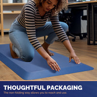 Woman in striped shirt smoothing out blue FEATOL anti-fatigue standing mat on office floor demonstrating non-folding roll packaging for easy unboxing and immediate use