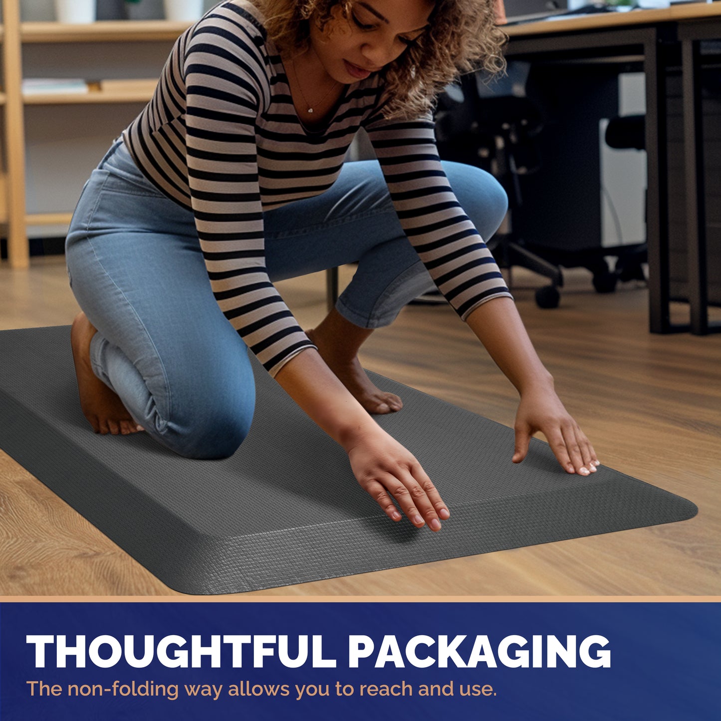 Woman in striped shirt kneeling and smoothing out gray FEATOL anti-fatigue standing mat on office floor, demonstrating thoughtful non-folding roll packaging for easy unboxing and immediate use