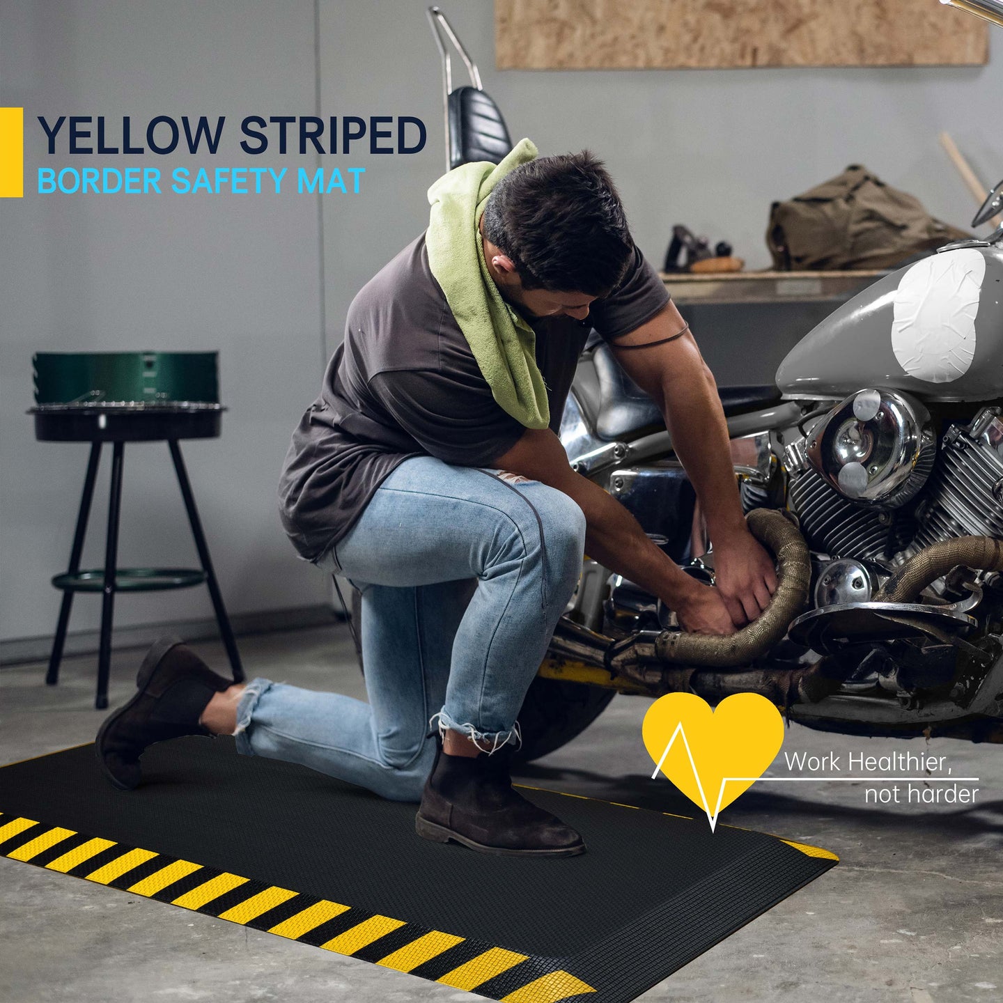 Man kneeling on black anti-fatigue mat with yellow striped border while working on motorcycle in garage