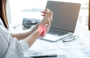 Woman experiencing wrist pain from long hours of office work and typing